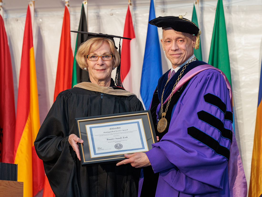President David Podell and Trustee Sandy Lish at Commencement, in front of flags