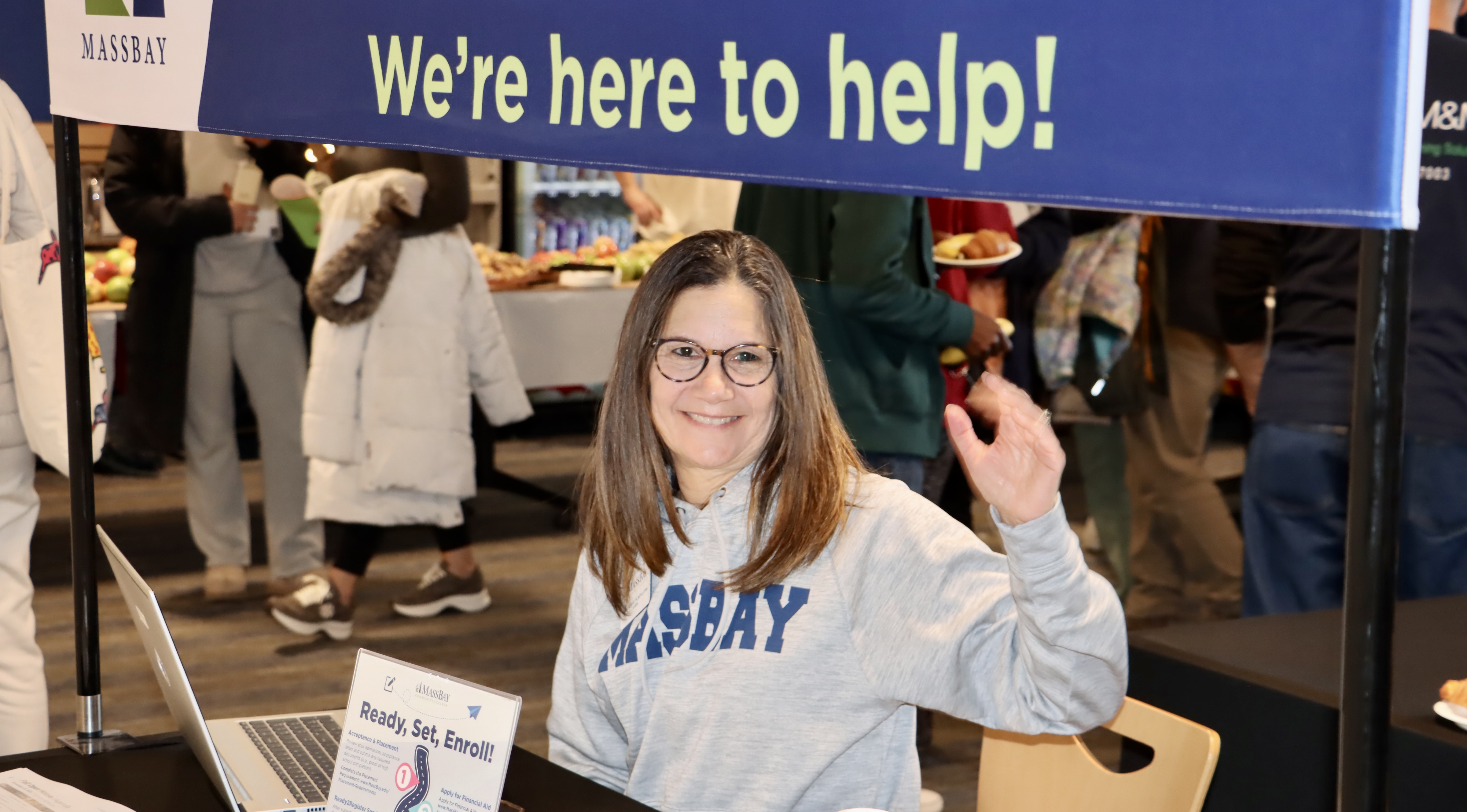 Friendly MassBay staff member waving from an information booth