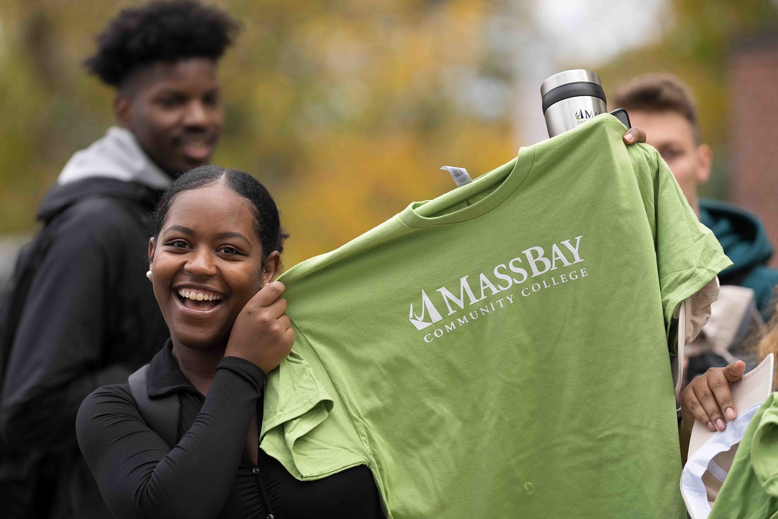 Students hold up MassBay t-shirt